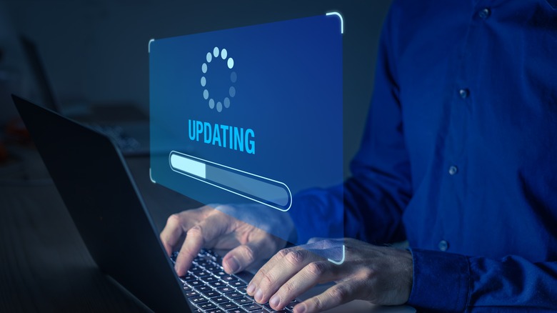 man typing on laptop with "updating" graphic