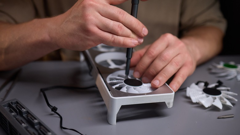 hands repairing a GPU fan