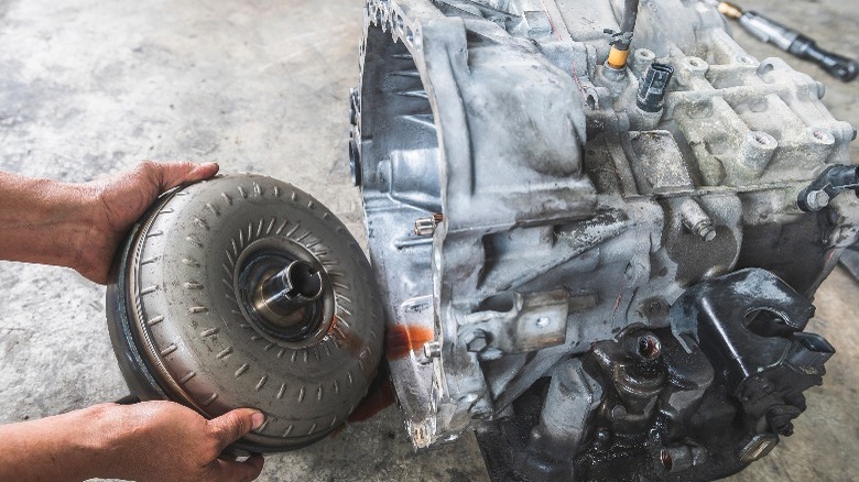 mechanic removing a torque converter from automatic transmission