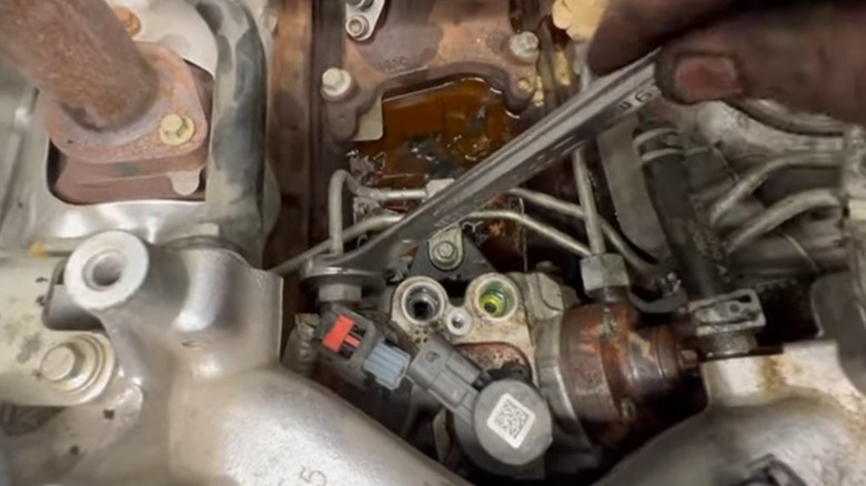 Mechanic using a wrench to loosen fuel lines preparing to remove a CP4 pump