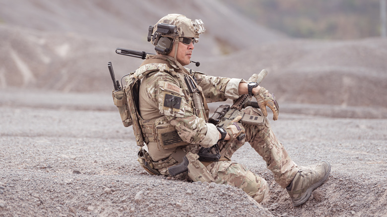 A soldier sits in the sand.