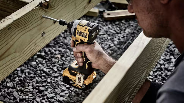 Person using a compact impact driver on wood