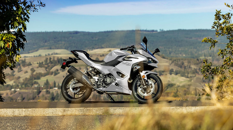 A Kawasaki Ninja 500 parked on a road with hills in background