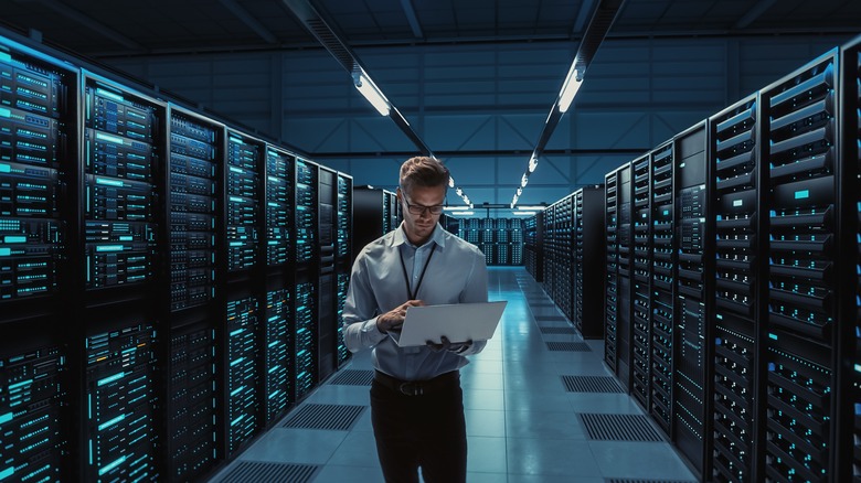 Man with a laptop standing in a server room