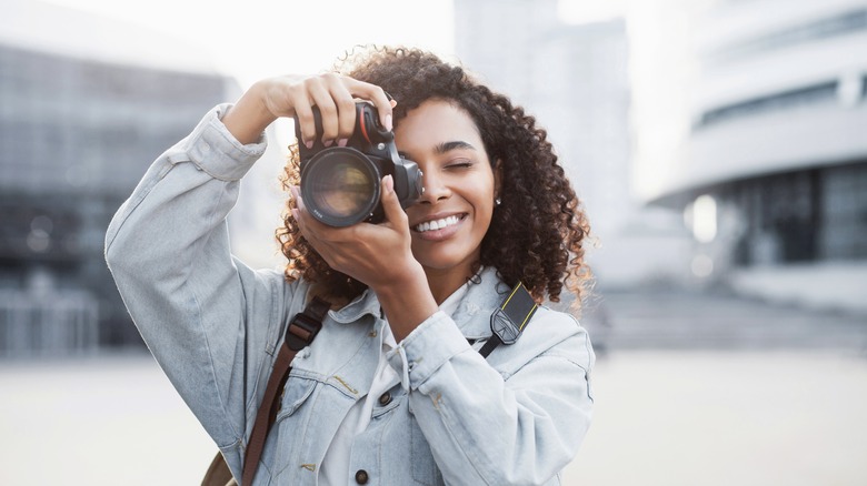 young woman holding camera to eye