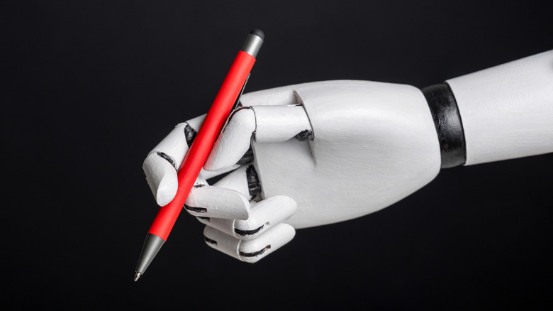 A robotic hand holding a ballpoint pen against a black background