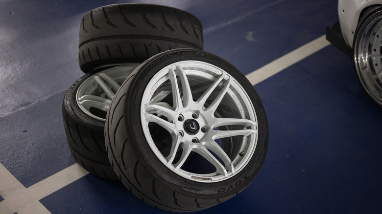 Aftermarket rims and tires lying on floor