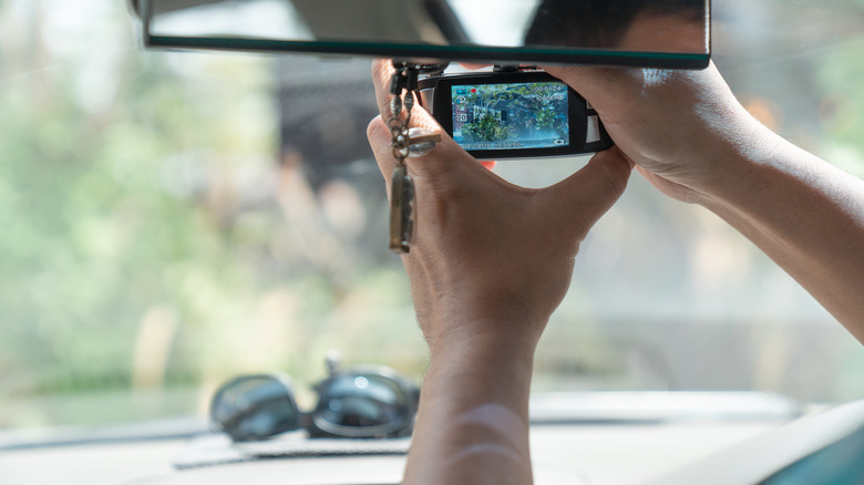 Dashcam being adjusted on front windshield