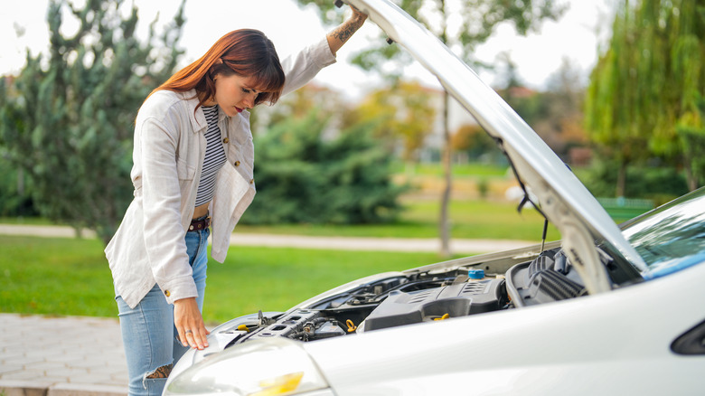 This woman is examining her car's engine, perhaps wondering how to make it perform better