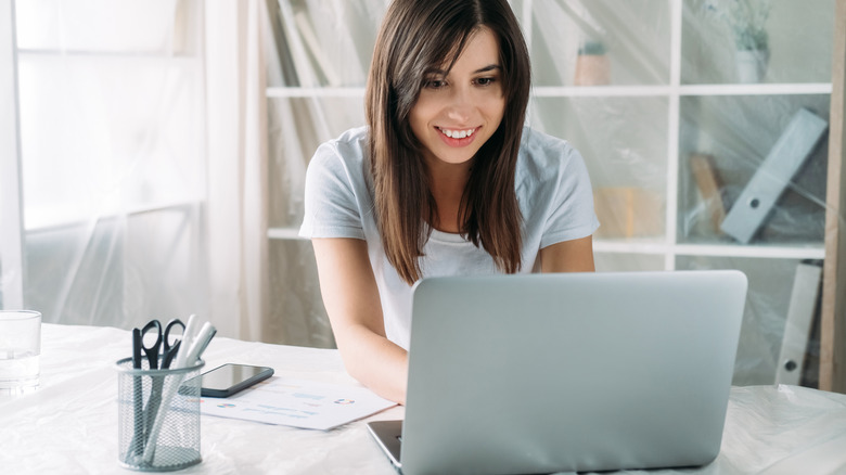 A young woman happily using her laptop with a case on her organized desk