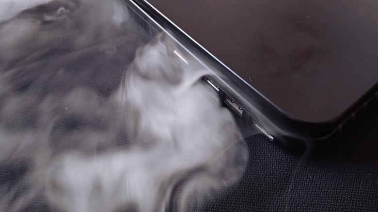 Smoke coming out of a folded laptop's ports and side