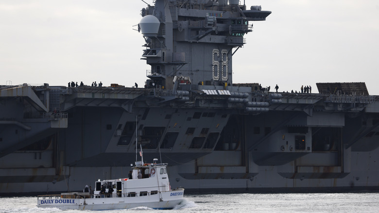 A fishing boat passes the USS Nimitz (CVN-68).