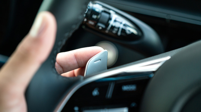 close up of hand operating a paddle shifter on a car