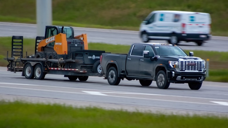 Pickup truck with attached trailer and construction equipment.