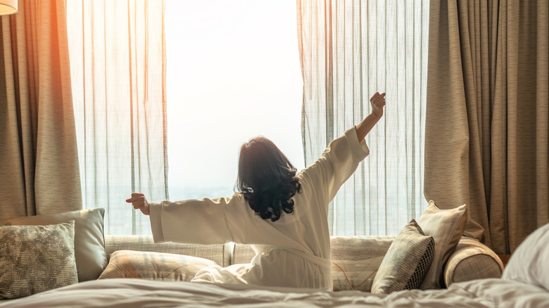 Person waking up to sunrise coming in through window