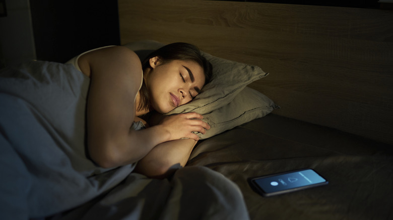 person asleep while a phone alarm is going off