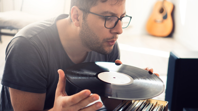 man blows dust off vinyl