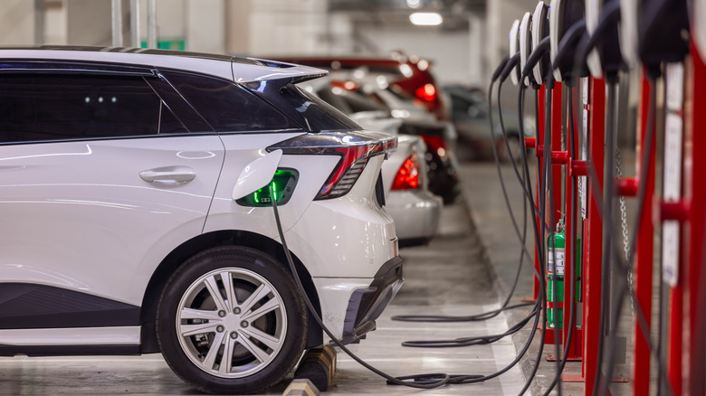 A white car hooked up to a fuel dispenser