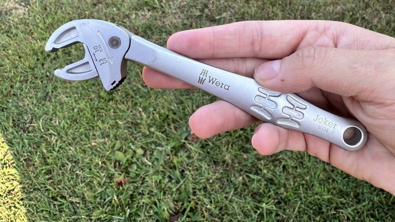 Holding a self setting wrench with a grassy background