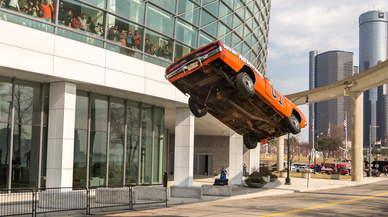 Orange dodge charger making a stunt jump in parking lot