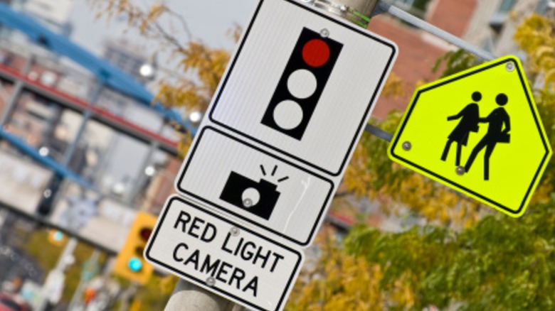 Pedestrian walking and red light camera signs