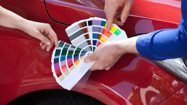 A color sampler in front of a red car.