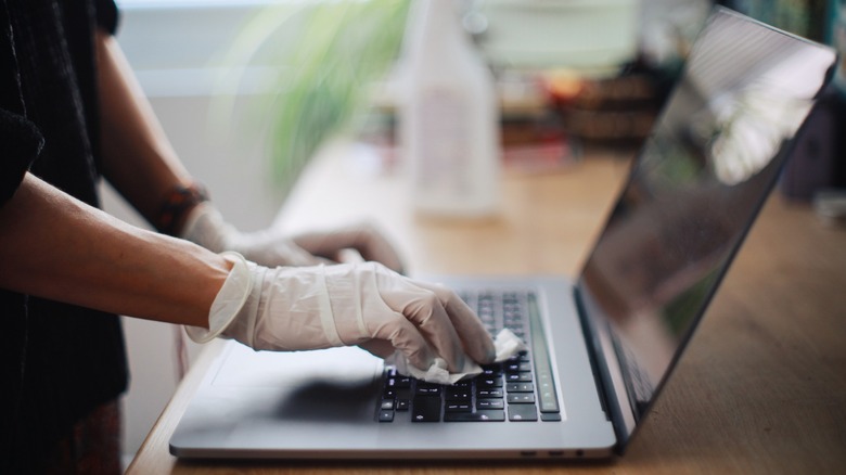 cleaning laptop with white latex gloves