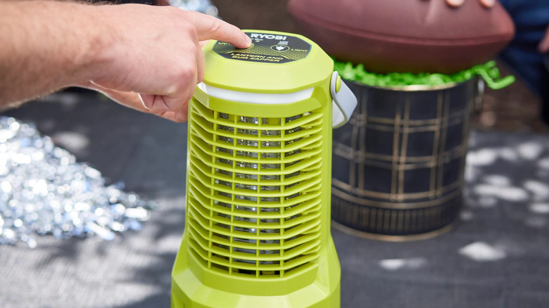 Person pressing button to start a Ryobi bug zapper