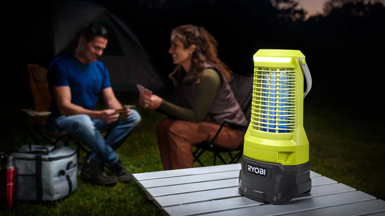 Man and woman camping with Ryobi bug zapper on a table