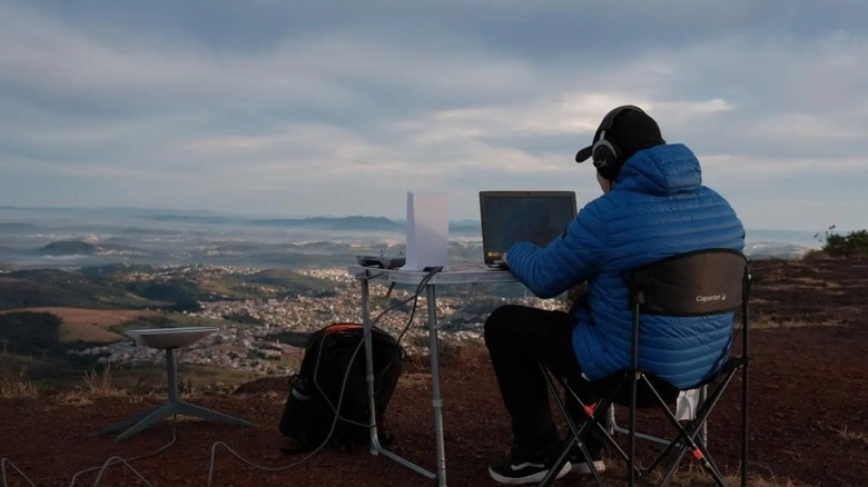 Man using Starlink outdoors while the skies are cloudy