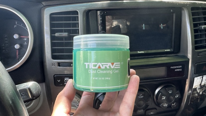 Holding up a jar of cleaning gel in a car