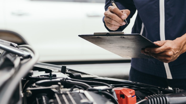 A zoomed in shot of a mechanic inspecting a car