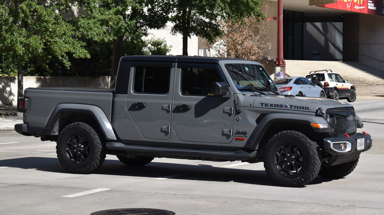 A grey and black Jeep Gladiator, cruising in the street