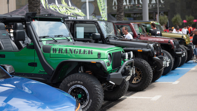 A green second generation Wrangler TJ parked among other vehicles