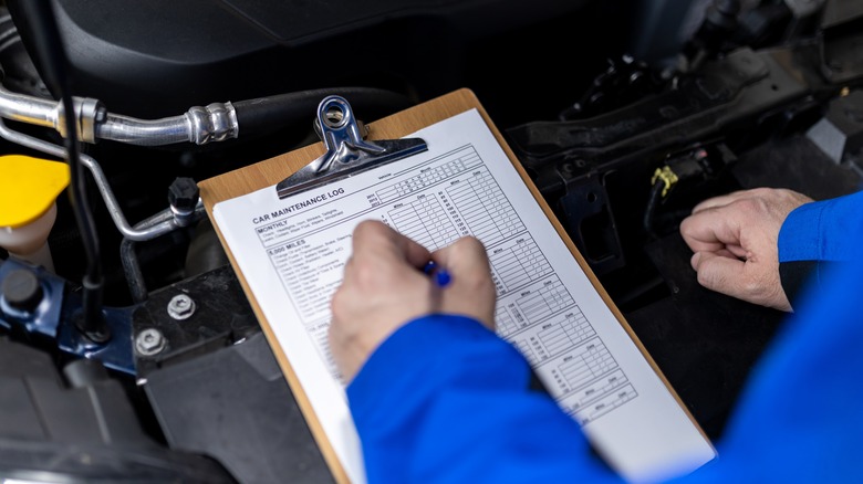 A mechanic looking over a maintenance log.