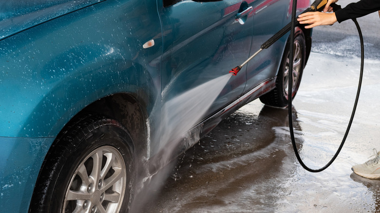 Cleaning a car with pressure washer nozzle positioned at a 45-degree angle