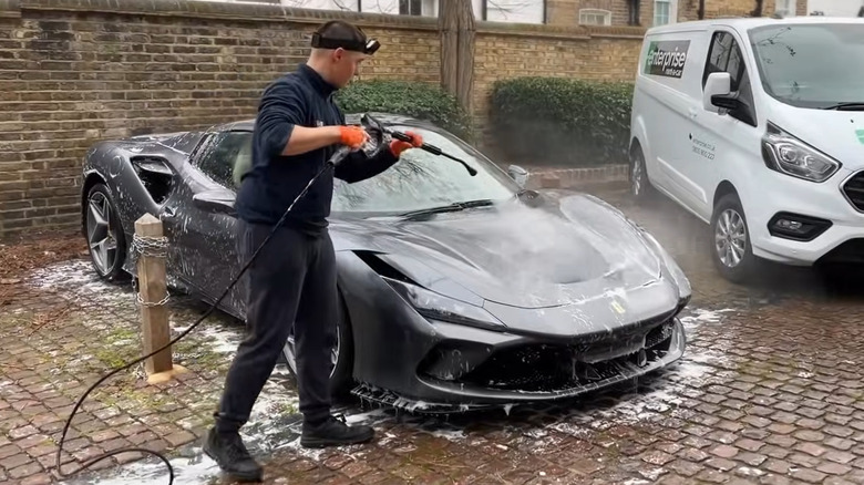 Man rinsing a Ferrari with pressure washer