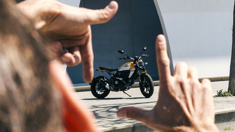 Hands making square over Ducati Scrambler 