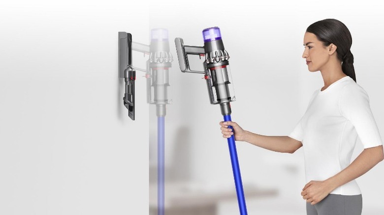 Woman placing Dyson vacuum on wall charger