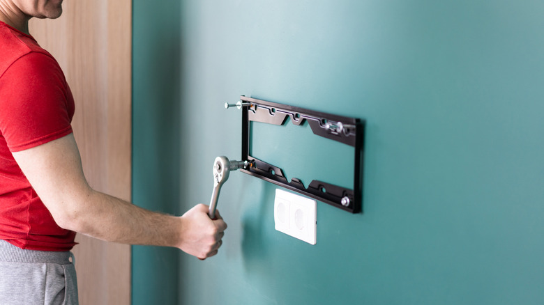 man attaching TV mount to a wall