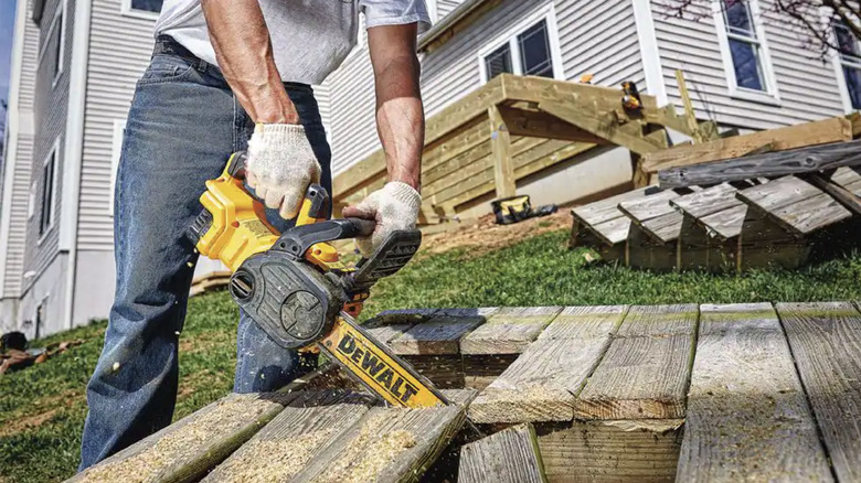 Man using electric chainsaw on wood