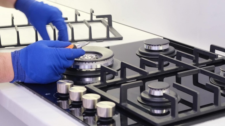 A repairman repairs a gas stove close-up.