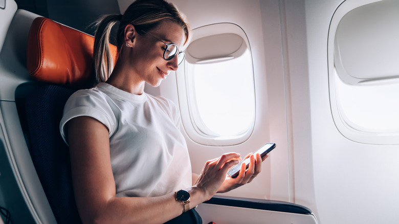 Passenger using smartphone on a flight. 