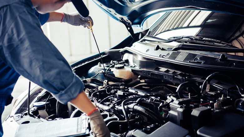 person checking oil on a car engine