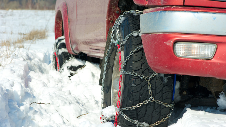 A red pickup truck with snow (tire) chains on stuck in deep snow.