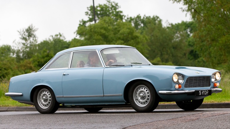 A blue Gordon-Keeble GT driving on a country road