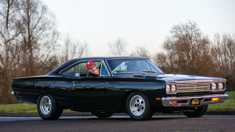 Black 1969 Plymouth Road Runner with driver on track