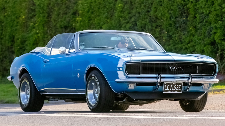 A blue 1967 Camaro convertible driving on street