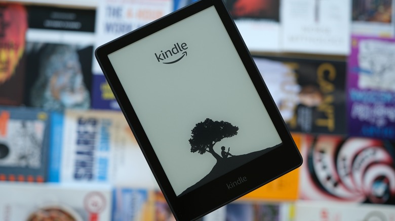 Amazon Kindle with various paperback books in the background