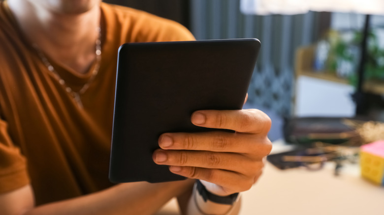 Man reading a book on an Amazon Kindle